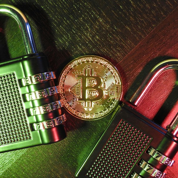 Hand holding a gold Ripple cryptocurrency coin against a dark leather background