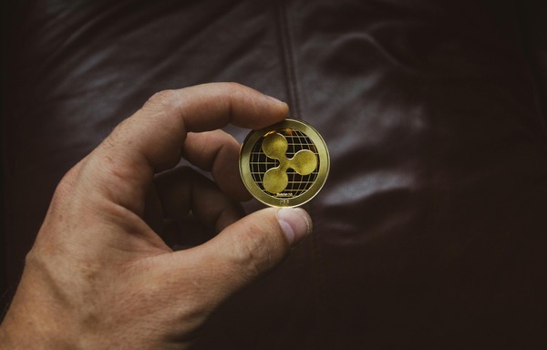 Hand holding a gold cryptocurrency coin against a dark background