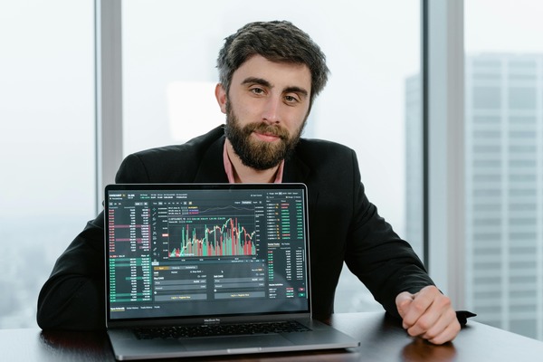 Man showing a laptop screen with a live cryptocurrency trading chart and order book