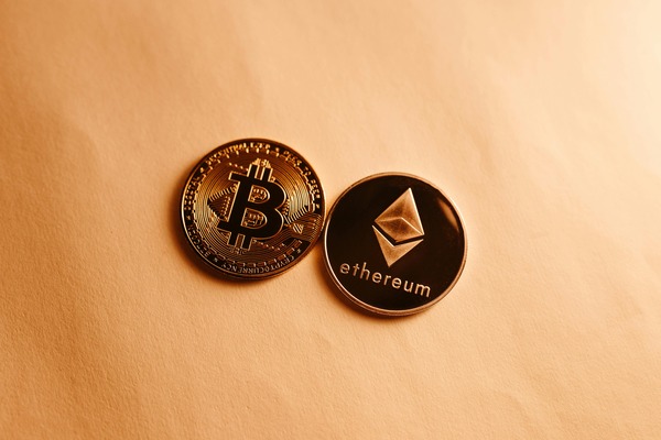 Bitcoin and Ethereum cryptocurrency coins placed together on a warm orange background