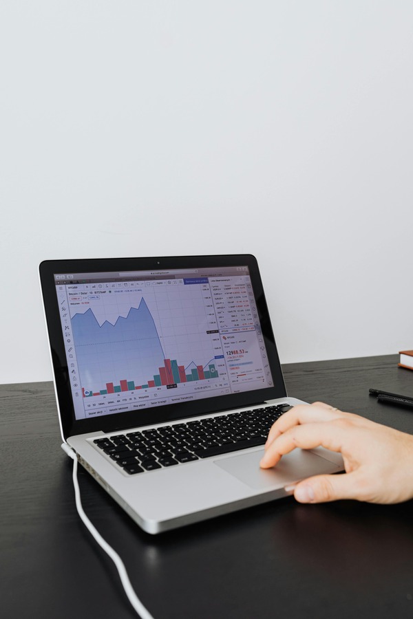Hand using a laptop trackpad while a bitcoin price chart is shown on screen