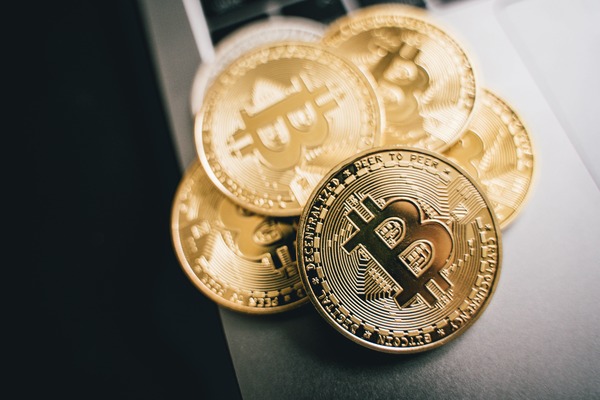 Pile of gold cryptocurrency coins resting on a laptop keyboard